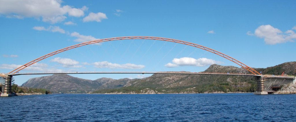 A slender bridge spanning water, mountains in the background